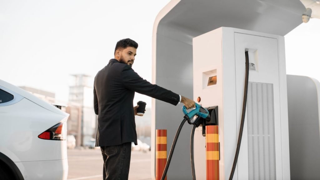 A driver plugging a charger into an electric car at one of the EV charging stations