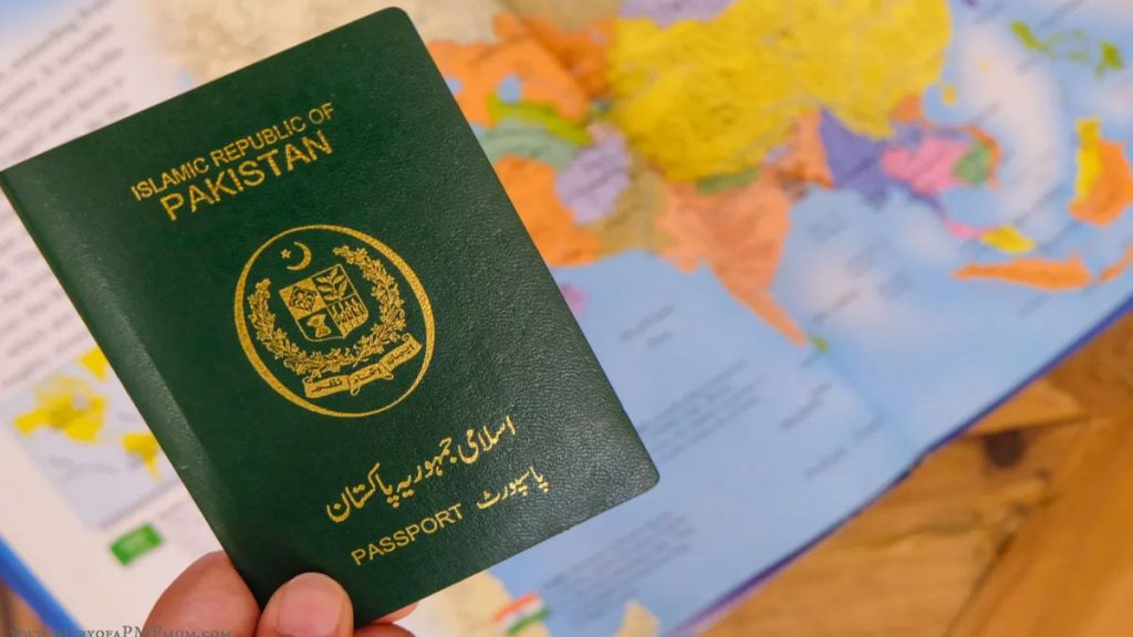 A green Pakistani passport held above a world map, illustrating new passport fees for UAE residents