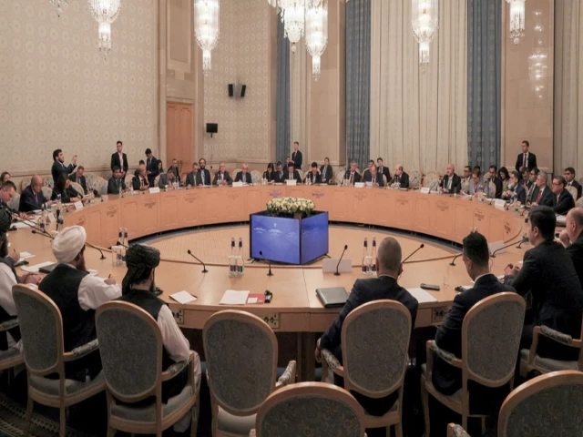 Delegates seated around a large circular table in an ornate hall with chandeliers at the Moscow Format talks on Afghanistan