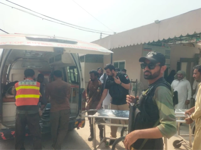 Rescue workers and armed police beside an ambulance and stretchers outside a hospital building in Dera Ismail Khan