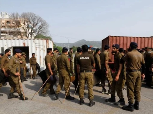 Police officers standing beside shipping containers used to block a road